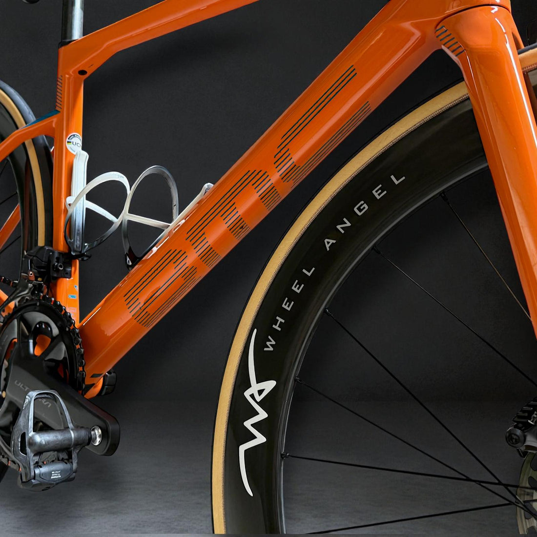 Close up of orange BMC road bike frame featuring Wheel Angel SLR carbon wheels and Vittoria Corsa Pro gumwall tires